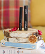 A pack of Green People Volumising Mascara on a log slice that has been placed on a pile of books.