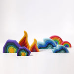 Grimm's Wooden Medium Rainbow side view with elements in the background on a grey background