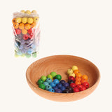 Rainbow coloured wooden Grimms beads in bag and in a wooden bowl on a cream background.