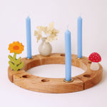 A Grimm's wooden celebration waldorf ring, with three Grimm's blue beeswax candles decorating it.