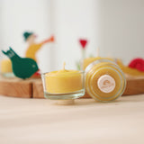 A closeup of beeswax tealights and holders, showing the plug base in front of a celebration ring.