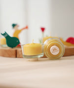 A closeup of beeswax tealights and holders, showing the plug base in front of a celebration ring.