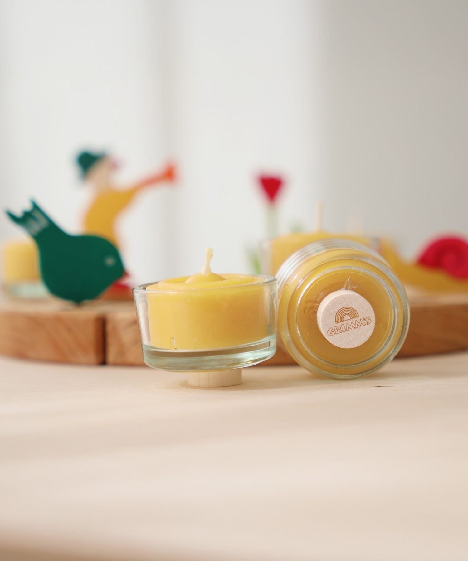 A closeup of beeswax tealights and holders, showing the plug base in front of a celebration ring.
