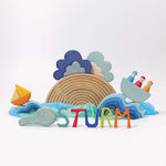 The Grimm's Wooden Weather Building Set set up along side the 12 piece natural rainbow and free standing letters, waves and Grimm's boat with 3 friends. The scene depicts a storm.