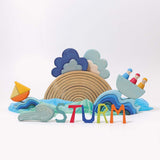The Grimm's Wooden Weather Building Set set up along side the 12 piece natural rainbow and free standing letters, waves and Grimm's boat with 3 friends. The scene depicts a storm.
