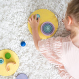 A top view of a child creating faces and abstract shapes with the Grimm's concentric wooden rings and circles