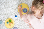A top view of a child creating faces and abstract shapes with the Grimm's concentric wooden rings and circles