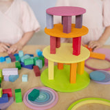 Two children playing with Grimm's wooden concentric circles and rings stacked into a colourful tower with wooden blocks, showcasing open-ended construction play.