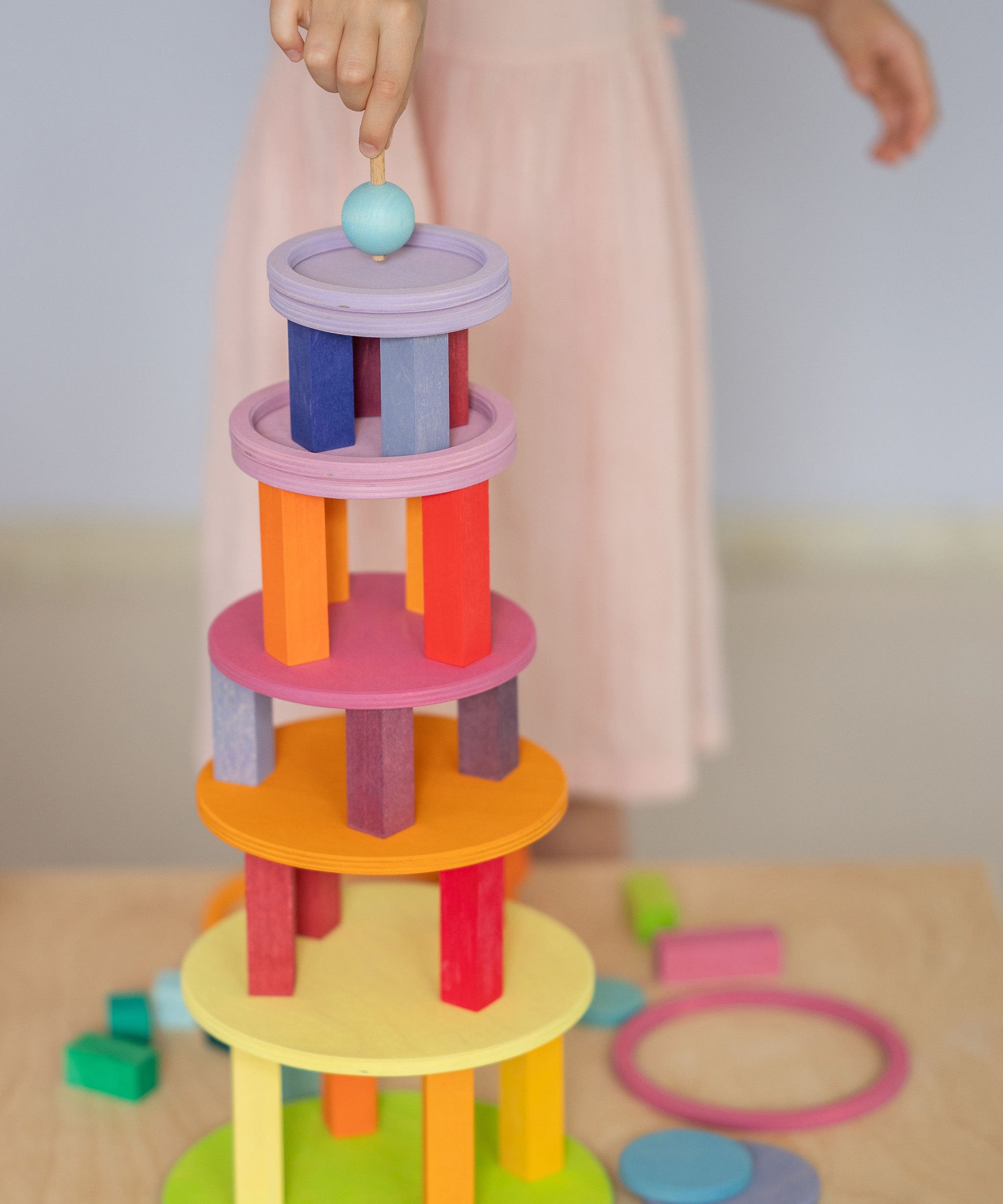 Grimm's wooden concentric circles and rings stacked into a colourful tower with wooden blocks, showcasing open-ended construction play.