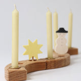 Grimms 100% beeswax candles in brass candle holders slotted in pieces from the decorative ring with a star and snowman figure creating a festive display