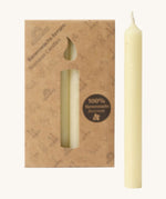 A close up of the Grimms 100% beeswax candles in cream with the cardboard packaging in the background.