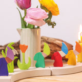 A row of Grimms decorative wooden dwarf figures with spring themed flowers on piece from the celebration ring