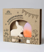 A Grimm's Easter Decorative Figure Set. the set includes a white bunny rabbit figure and a Batik Orange and purple coloured egg. The figures are shown in their cardboard packaging sleeve.