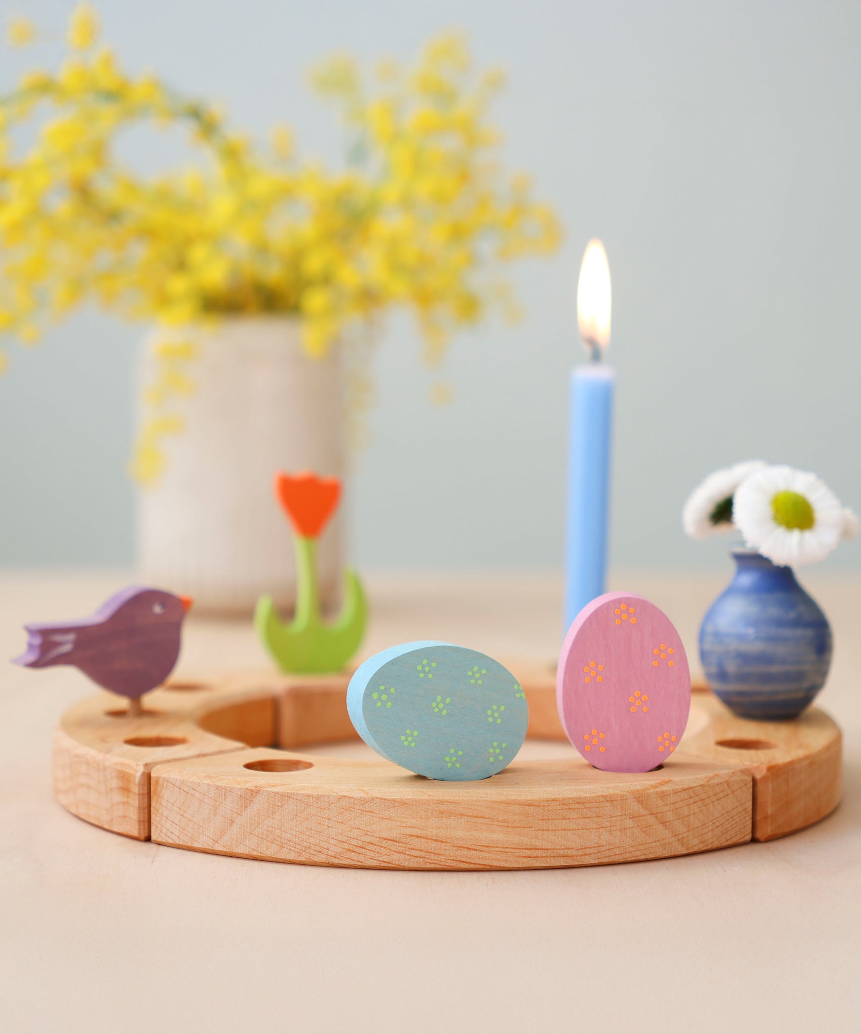Grimm's pink and blue Floral Duo Easter Eggs Decorative Figure Set. Both eggs are placed on a wooden Grimm's celebration ring with other figures and a blue candle seen in the background.