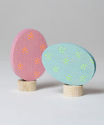 Grimm's Floral Duo Easter Eggs Decorative Figure Set. One egg is blue with light green dotted flower details and is side laying on it's base.  The other egg is pink with orange dotted flower details and is upright on it's base.