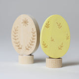 Grimm's Ornamental Duo Easter Eggs Decorative Figure Set. One egg is left natural withe floral themed outline details, the other painted in a light yellow with leaf outline details.