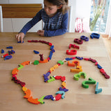 A child playing with the Grimm's Figures For Counting & Story Telling on a wooden table.