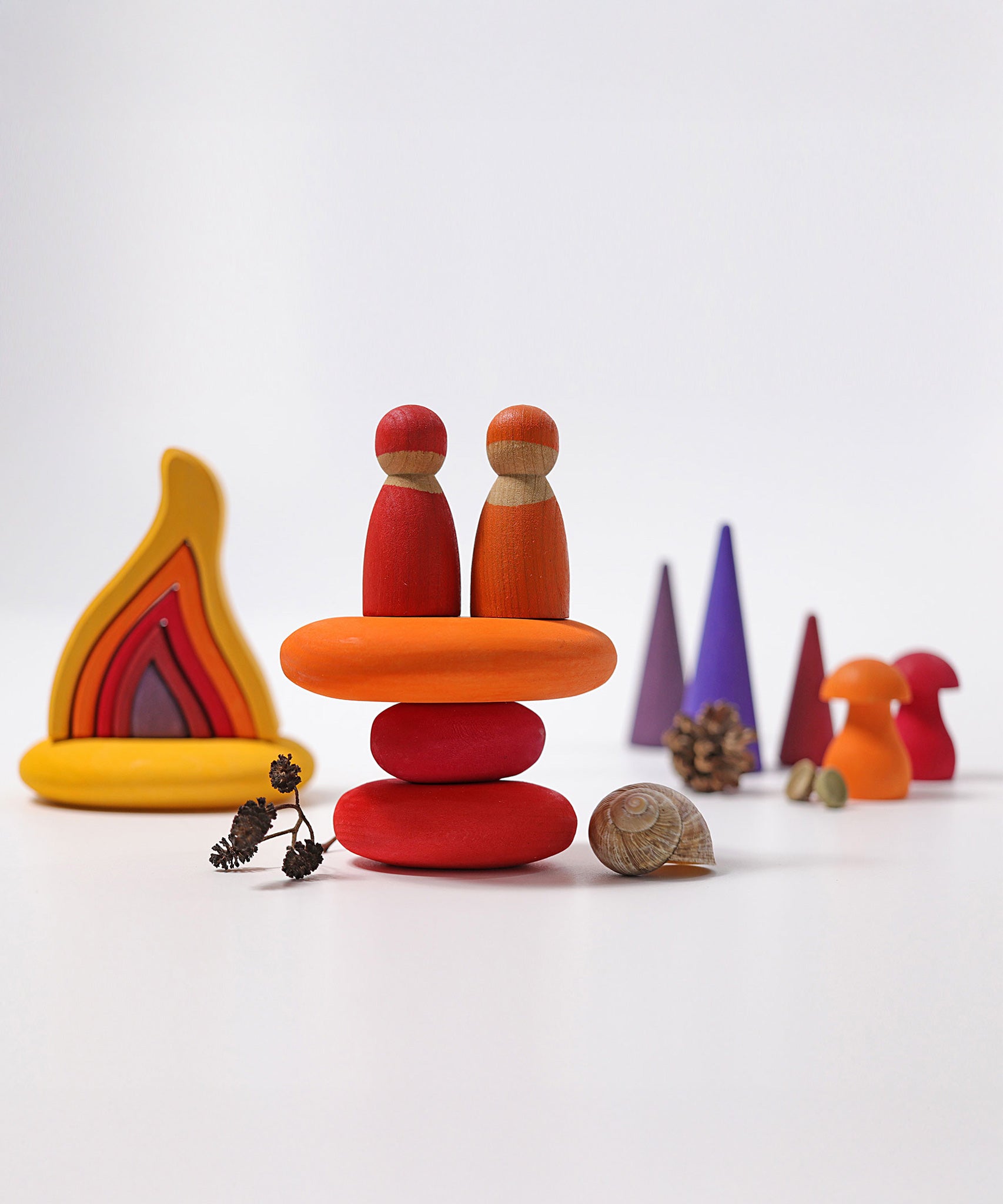 The Grimm's Fire Pebbles Building Set shown amongst a small world play set up alongside Grimm's friends, fire, forest and mushrooms.