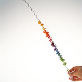 An adult holding one end of the giant Grimms spirelli available at Babipur. This  winding metal wire comes with coloured disks that make a noise when tipped over.