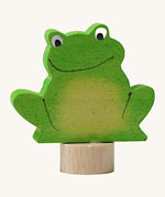 A Grimms green frog wooden decorative figure with playful features and a small base stand to slot into a decorative ring