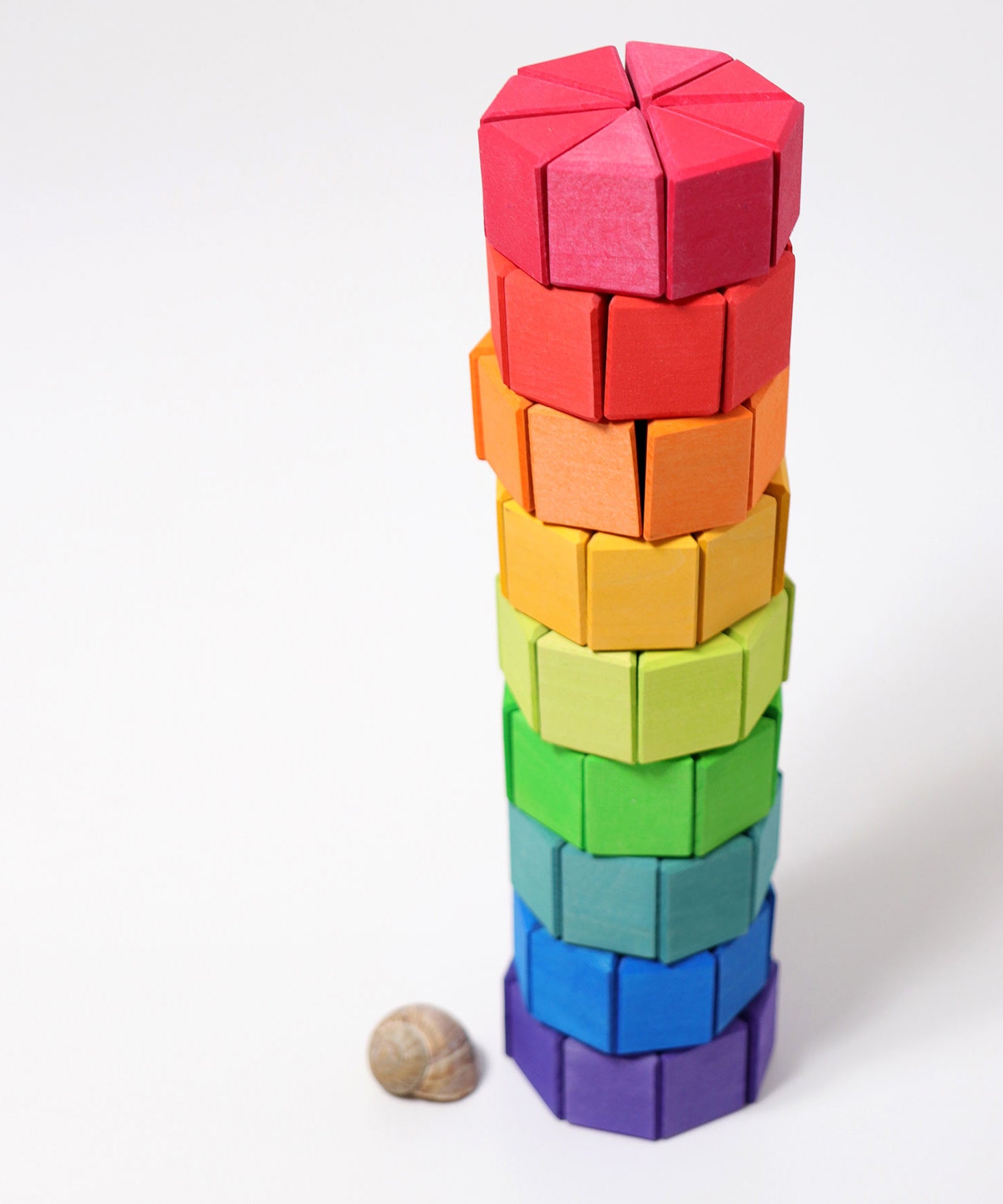 The triangular shaped wooden blocks from the Grimm's Large Octagon Puzzle Set stacked up to create a tower.