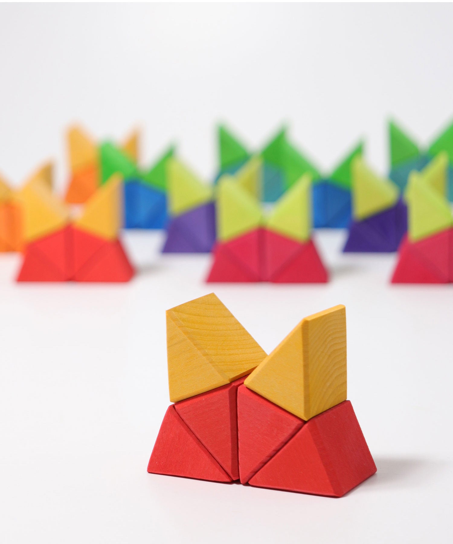 The triangular shaped wooden blocks  from the Grimm's Large Octagon Puzzle set used to create a stack that  resembles a cat's head.