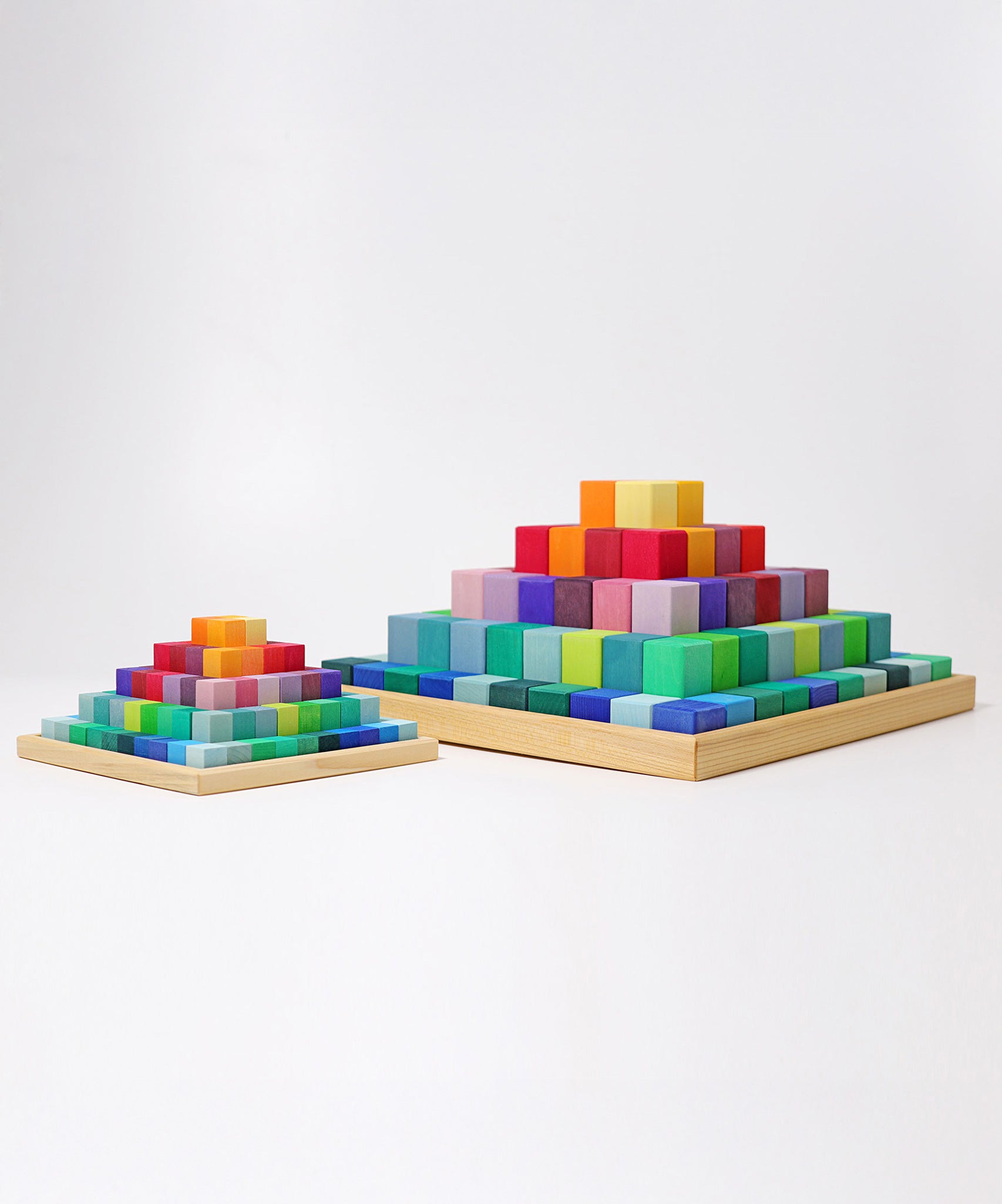The large Grimm's rainbow coloured Large Stepped Pyramid wooden toy building block set pictured next to a small version. These Grimm's toys are part of a wide range of wooden toys available here at Babipur.