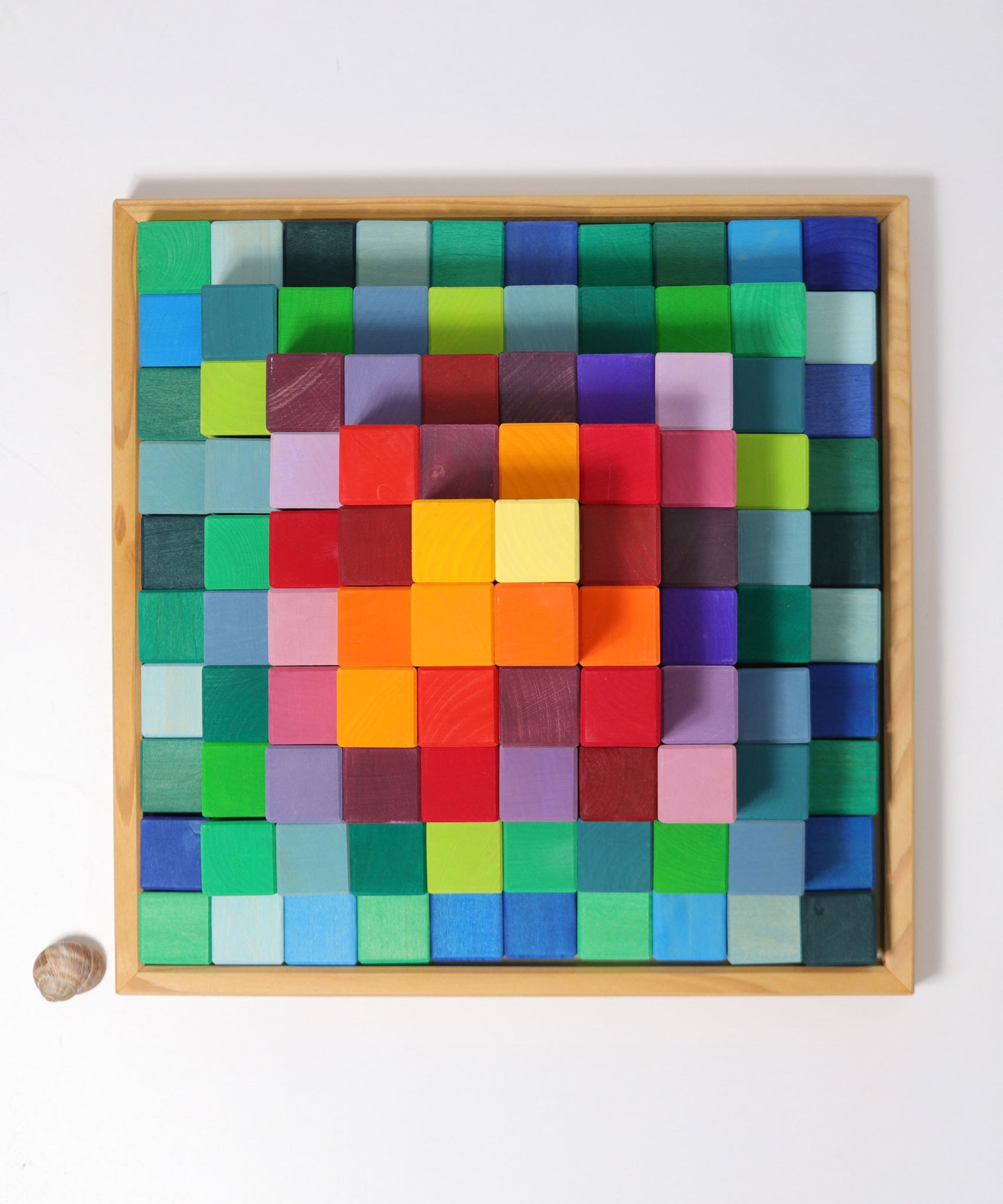 An overhead view of the Grimm's rainbow coloured Large Stepped Pyramid wooden toy building block set in the wooden storage tray. These Grimm's toys are part of a wide range of wooden toys available here at Babipur.