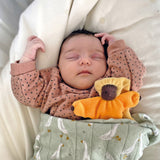 A baby is fast asleep and is cuddled with Grimm's Lavender Doll Sun