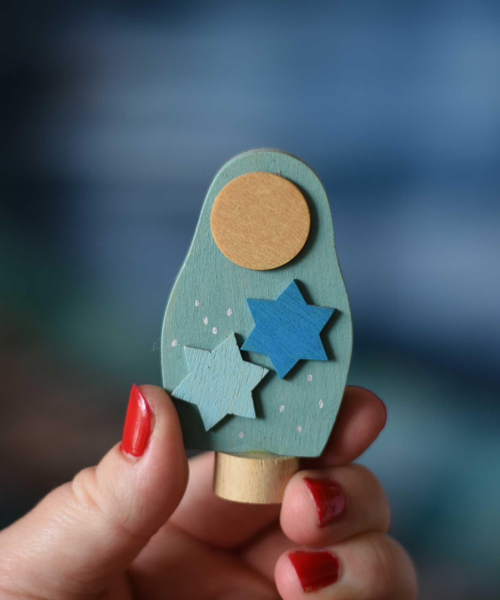 A Grimm's Matryoshka Stars Decorative Figure shown in an adult's had for scale.
