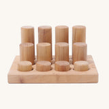 Different sized Grimms natural rollers on a wooden frame on a cream background.