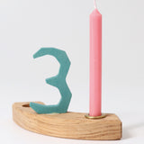 A pink Grimm's Old Rose 10% Beeswax Candles placed on a pieces of a natural celebration ring with a number 3 decorative figure in blue.