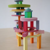 Tall pastel tower built with Grimm's wooden circles, rings, and building blocks, encouraging STEM learning and coordination.