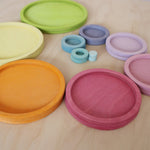 Grimm's wooden toy set showing pastel circles and rings grouped by size and colour, perfect for educational colour sorting games.