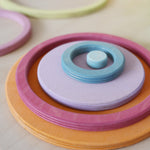 Nested Grimm's wooden circles and rings in pastel colours, demonstrating Montessori-inspired stacking and nesting activities.