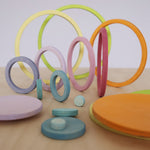 Grimm's pastel wooden rings standing upright in a line, showing size sorting and early STEM play for kids.