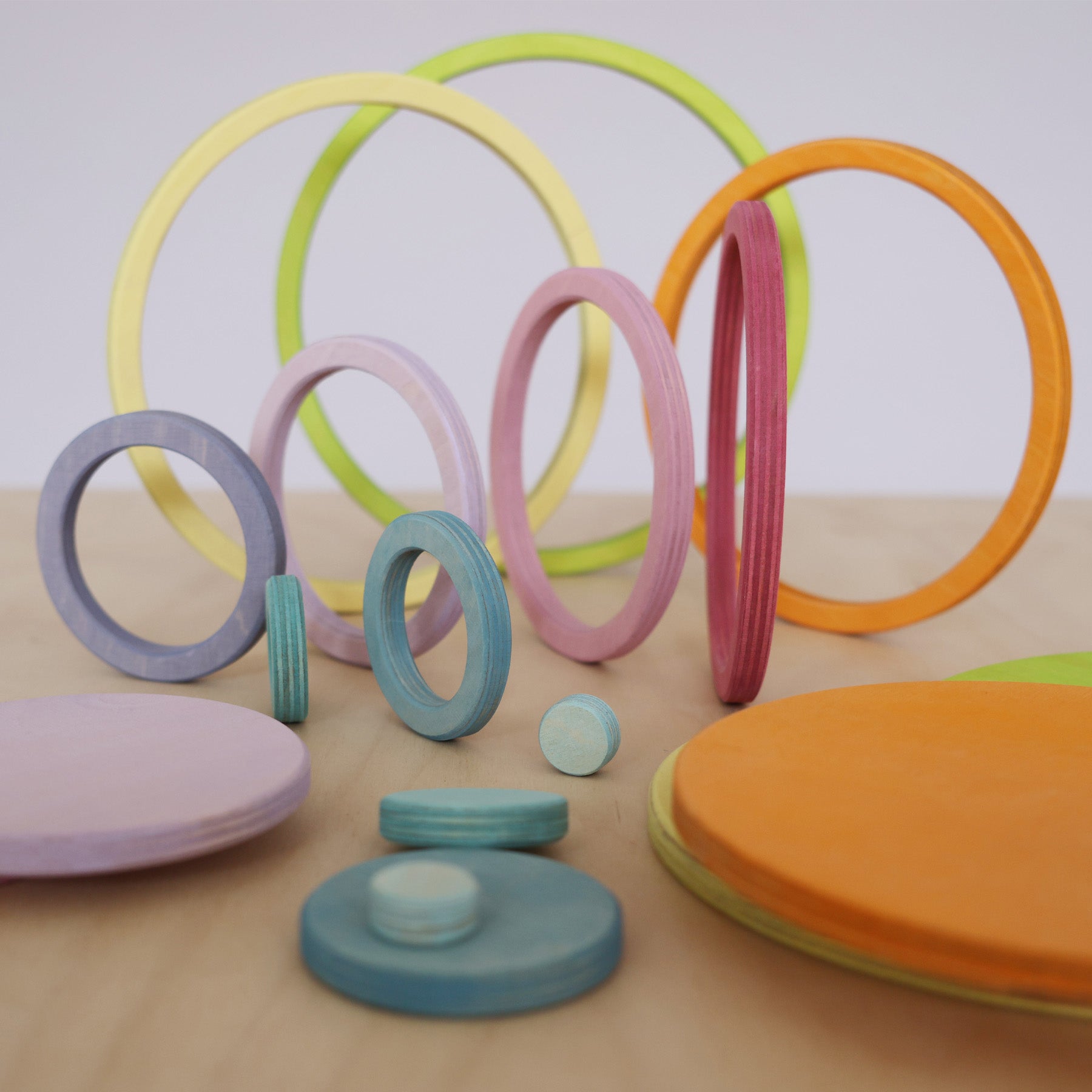 Grimm's pastel wooden rings standing upright in a line, showing size sorting and early STEM play for kids.