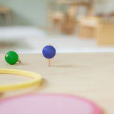 A green and purple coloured rainbow spinning tops in motion on a wooden surafce. These Grimm's toys are part of a wide range of wooden toys available here at Babipur.