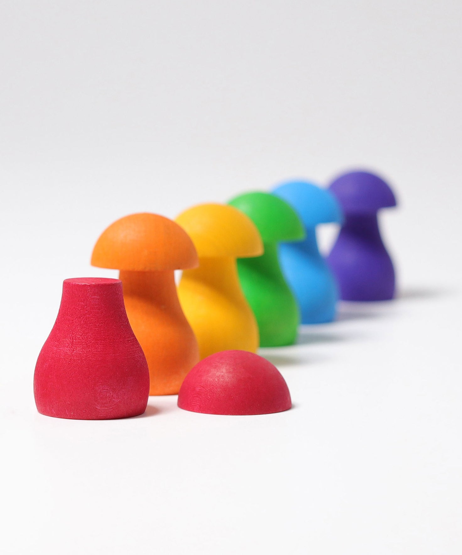The mushrooms from the Grimm's Rainbow Mushrooms Sorting Game all lined up next to each other.