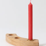 A single red Grimm's candle placed on a piece of natural celebration ring.