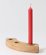 A single red Grimm's candle placed on a piece of natural celebration ring.