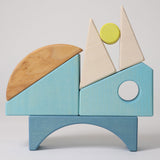 The wooden blocks from the Grimm's Building Set in Blue stacked up on top of each other. A set of wooden blocks that form a sailing boat when placed in the blue coloured storage tray.