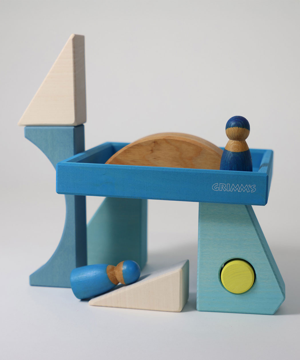 The blocks from the Grimm's Building Set Blue used in a small world play scene with two Grimm's friends wooden peg dolls. These Grimm's wooden block sets are part of a wide range of wooden toys available here at Babipur.