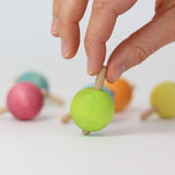 A hand ready to spin the green pastel wooden spinning top from Grimm's.