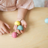 A child holding three of the pastel rainbow wooden spinning tops from Grimm's.