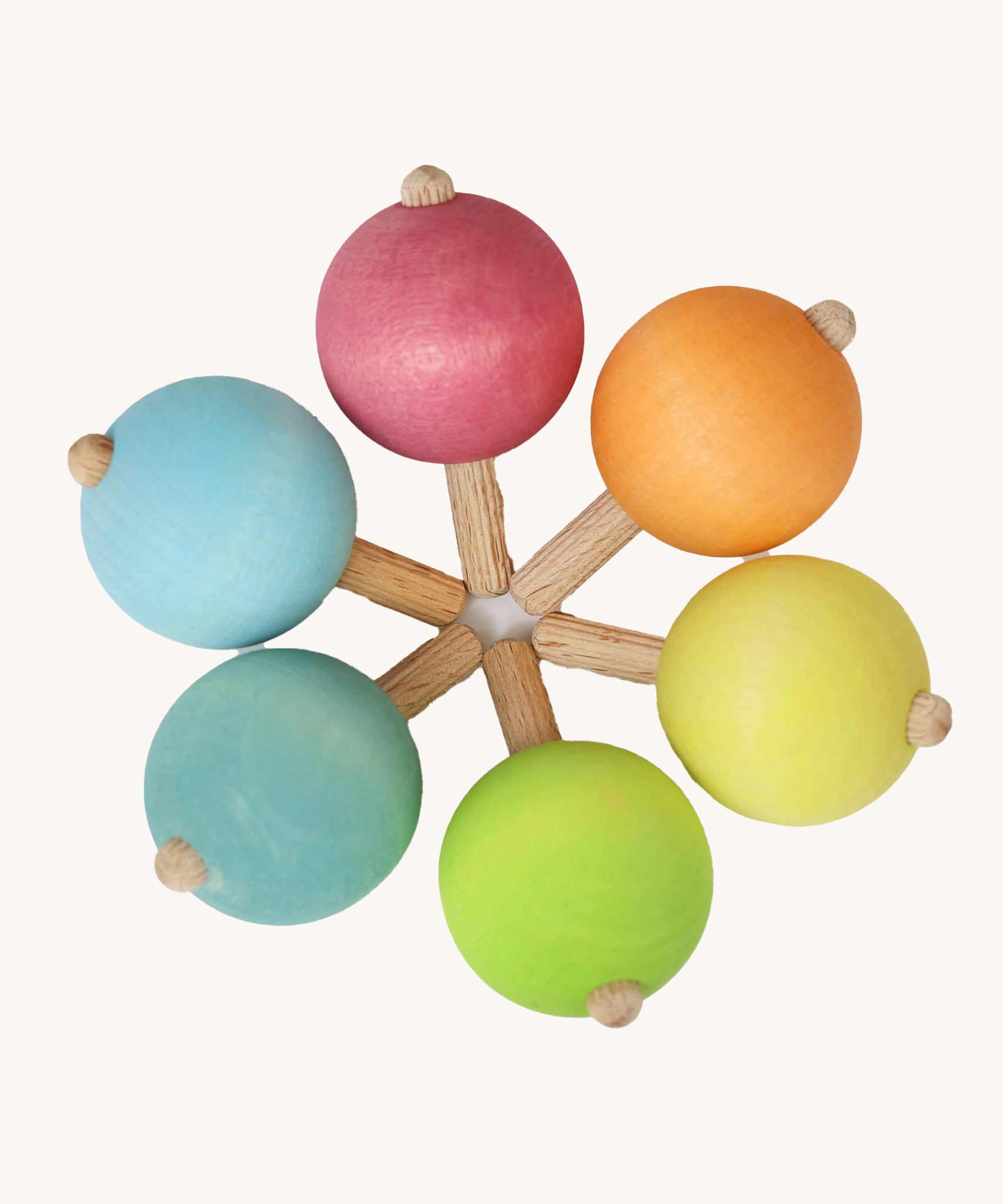 A set of six traditional wooden spinning tops from Grimm's, in pastel rainbow colours and arranged in a circle.