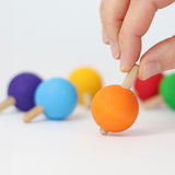 A hand ready to spin the orange wooden spinning top from Grimm's.