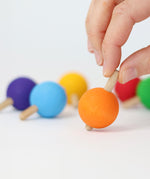 A hand ready to spin the orange wooden spinning top from Grimm's.