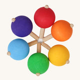A set of six traditional wooden spinning tops from Grimm's, in rainbow colours and arranged in a circle.