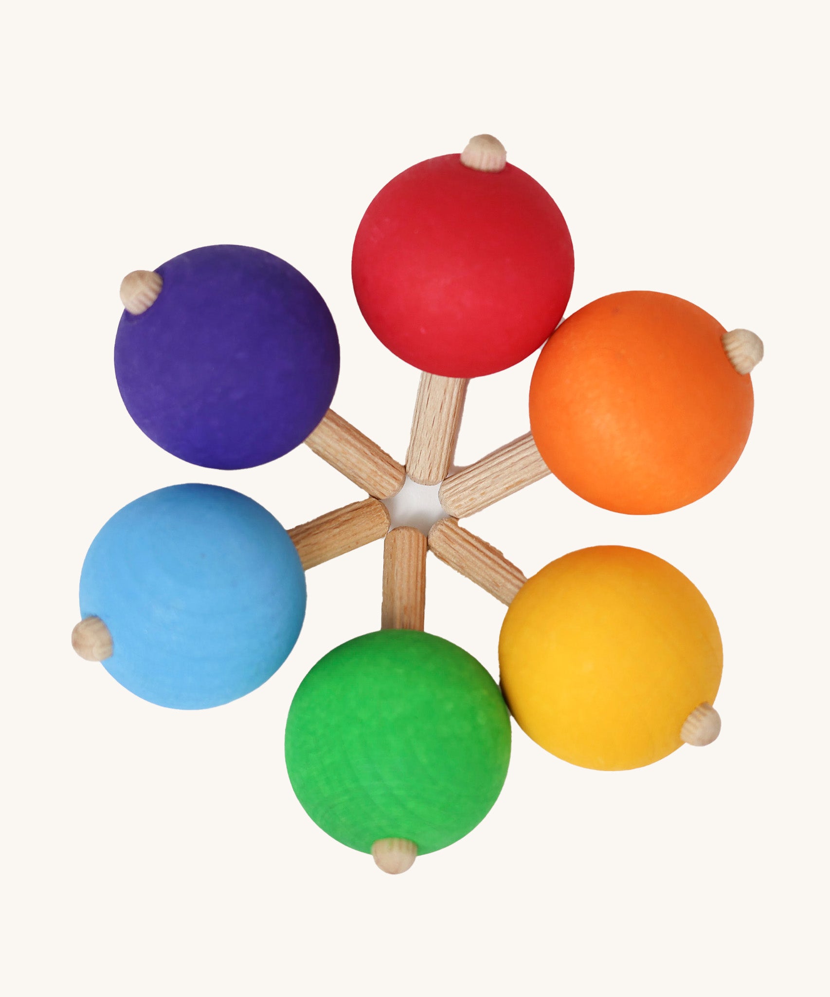 A set of six traditional wooden spinning tops from Grimm's, in rainbow colours and arranged in a circle.